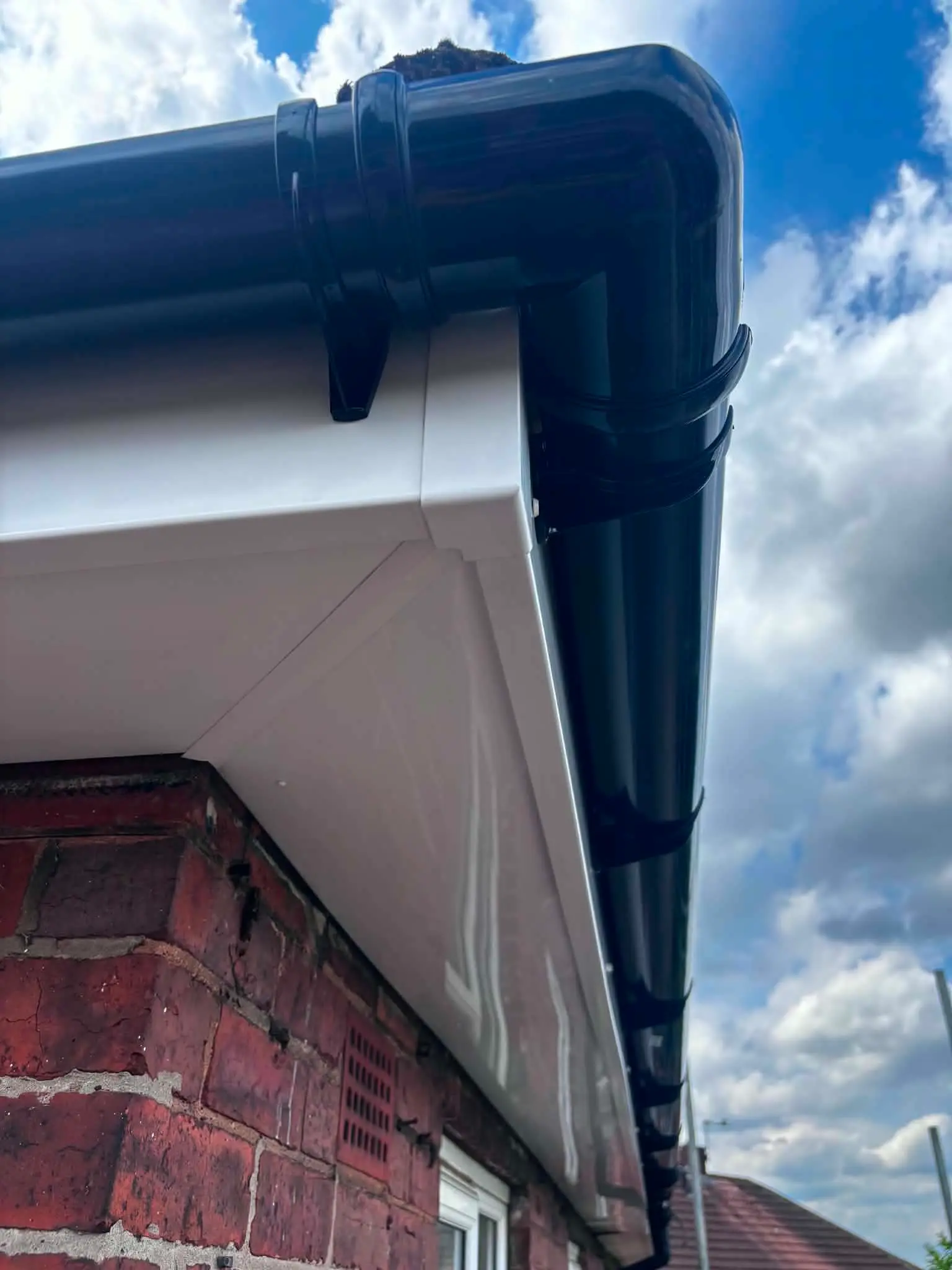New white fascia and soffit with black guttering and downpipe after roofline replacement