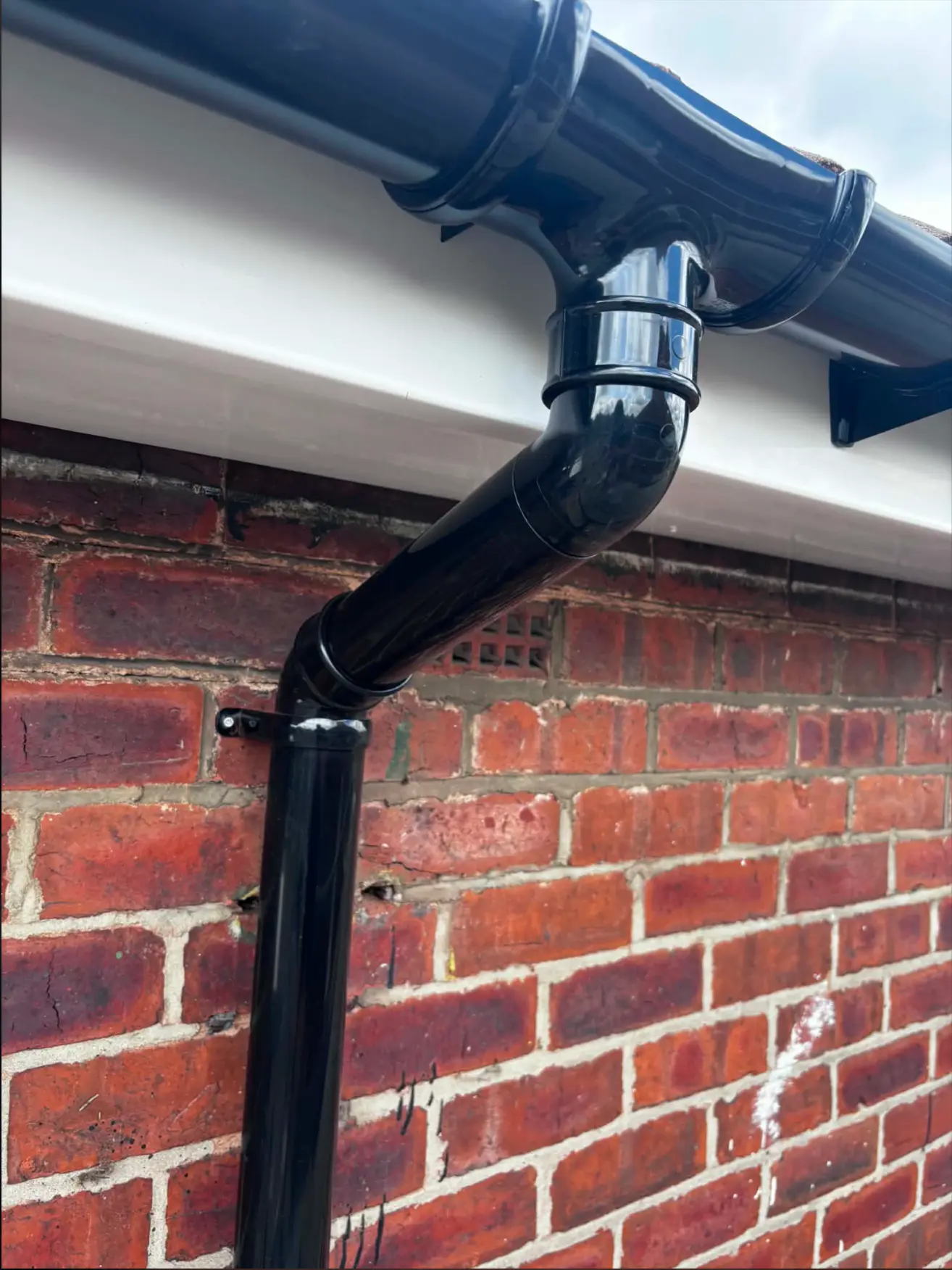New white fascia and soffit with black guttering and downpipe after installation