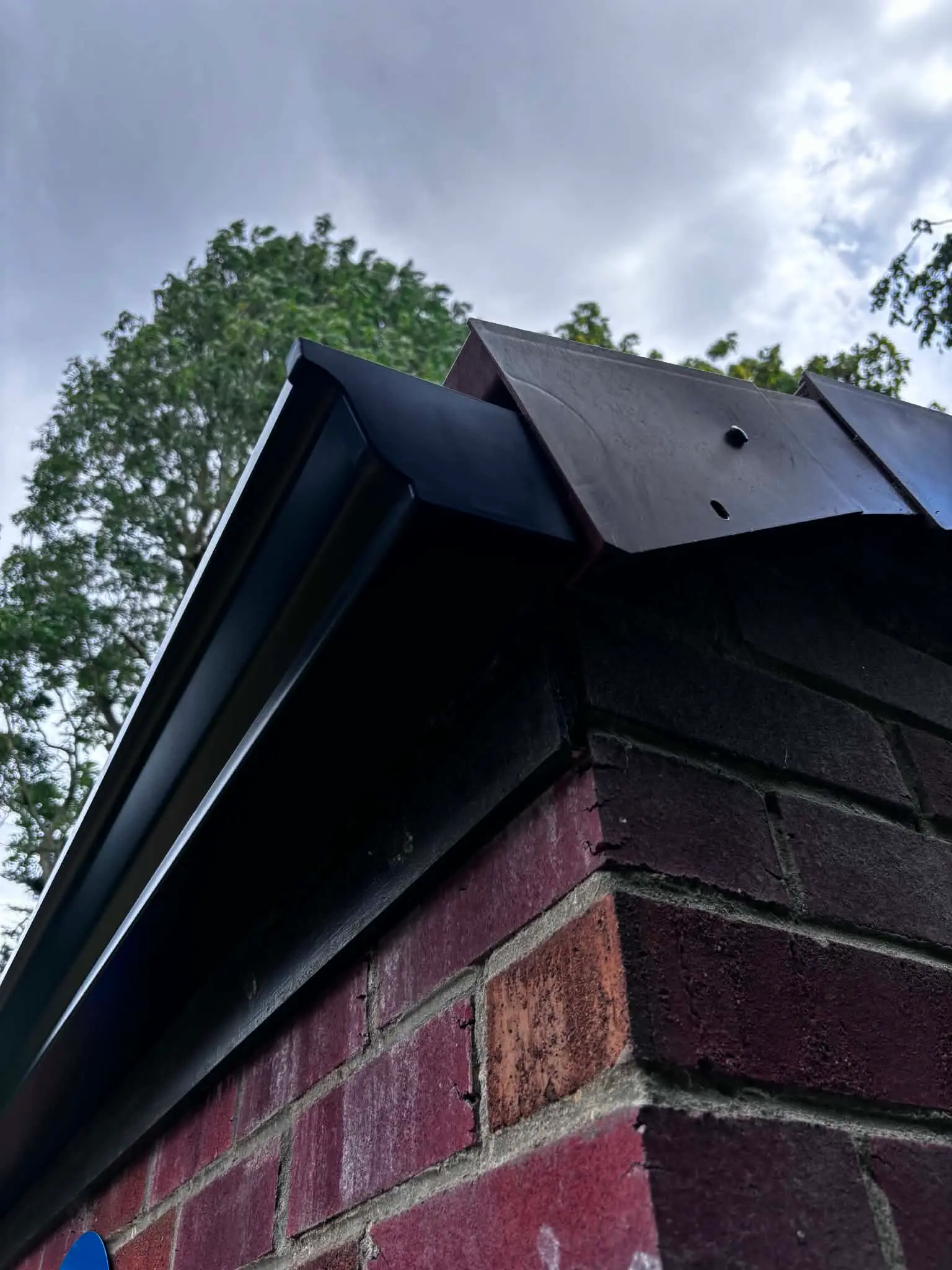 Neat black gutter end finish on a brick garage gable after installation work