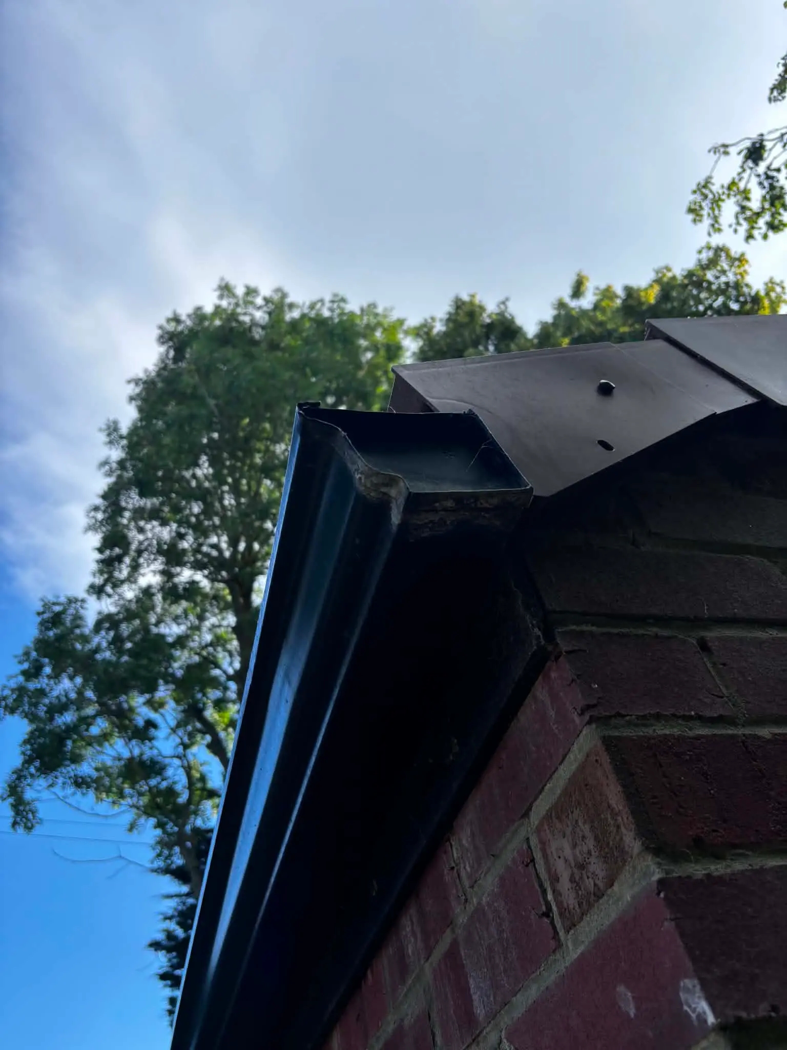 Older gutter end detail on a brick garage gable before improvement work
